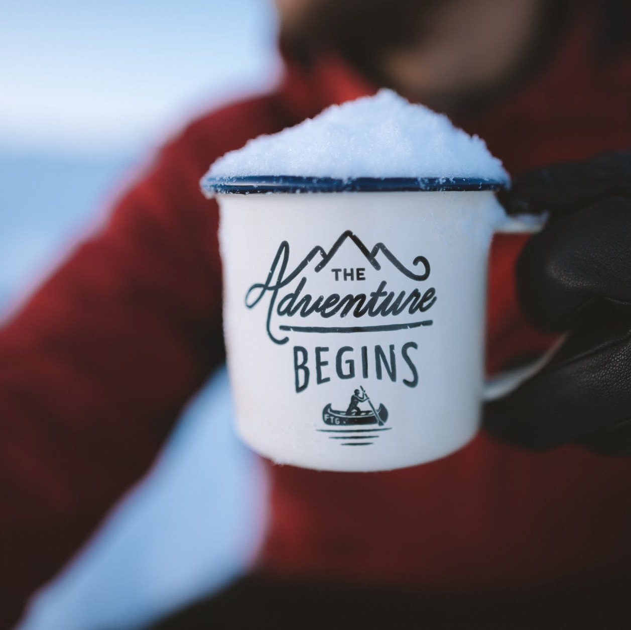 selective focus photography of person holding the adventure begins mug